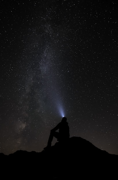 a person sitting on a mountain looking at the stars in the sky