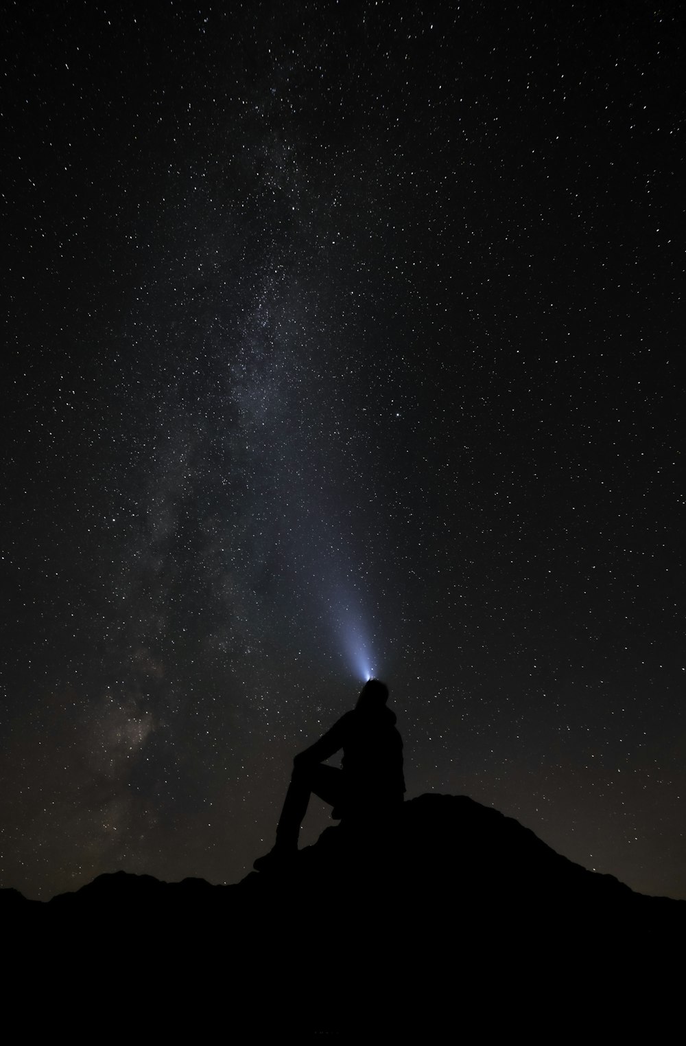 Una persona seduta su una montagna che guarda le stelle nel cielo