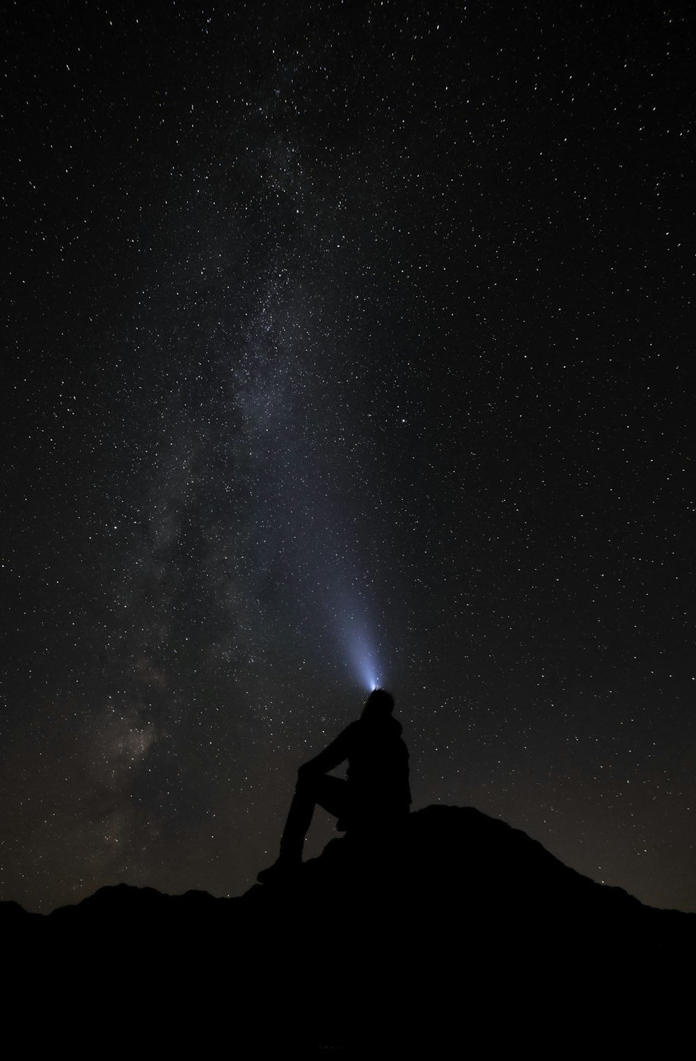 山に座って空の星を見ている人