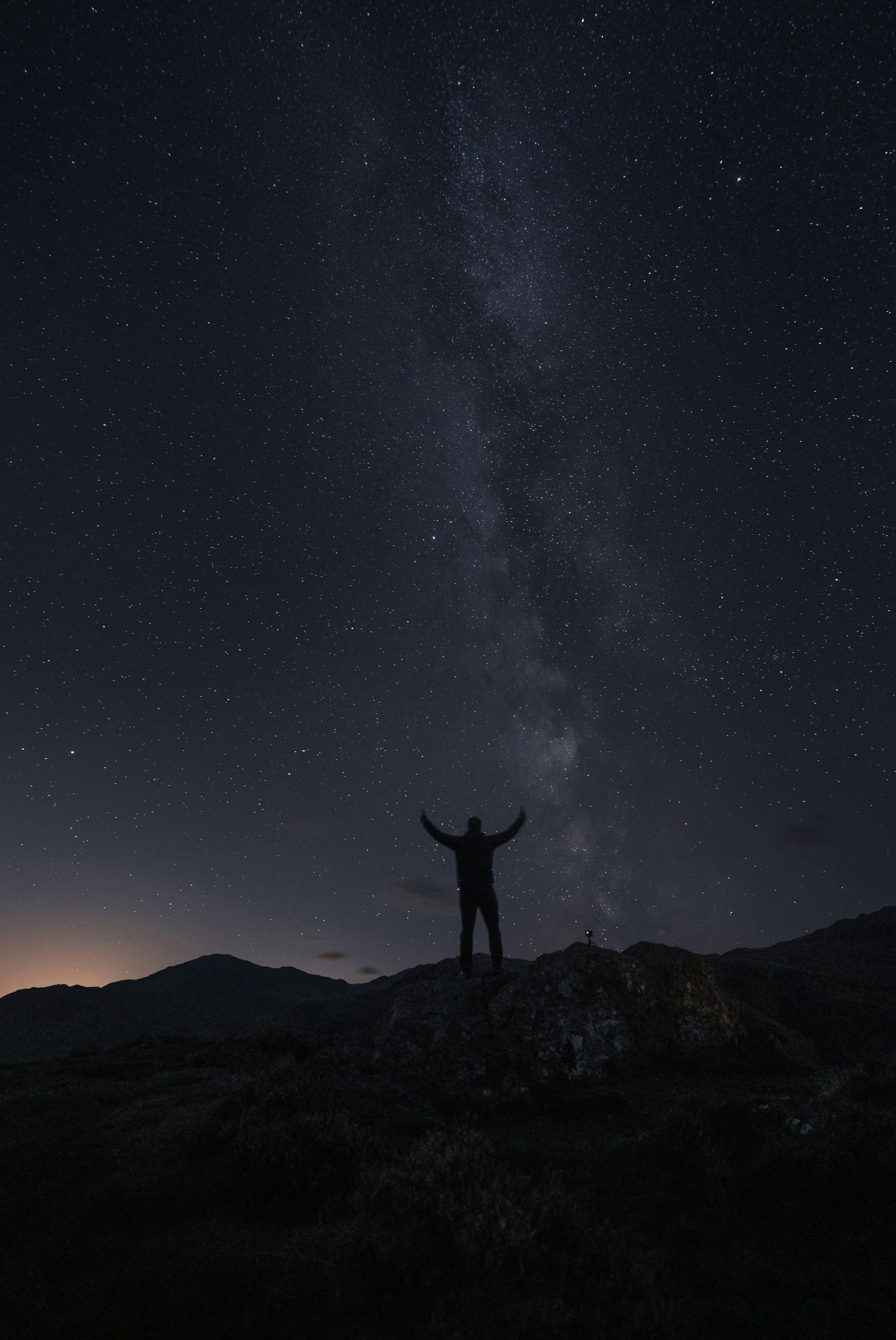 a person standing on a rock with a starry sky above