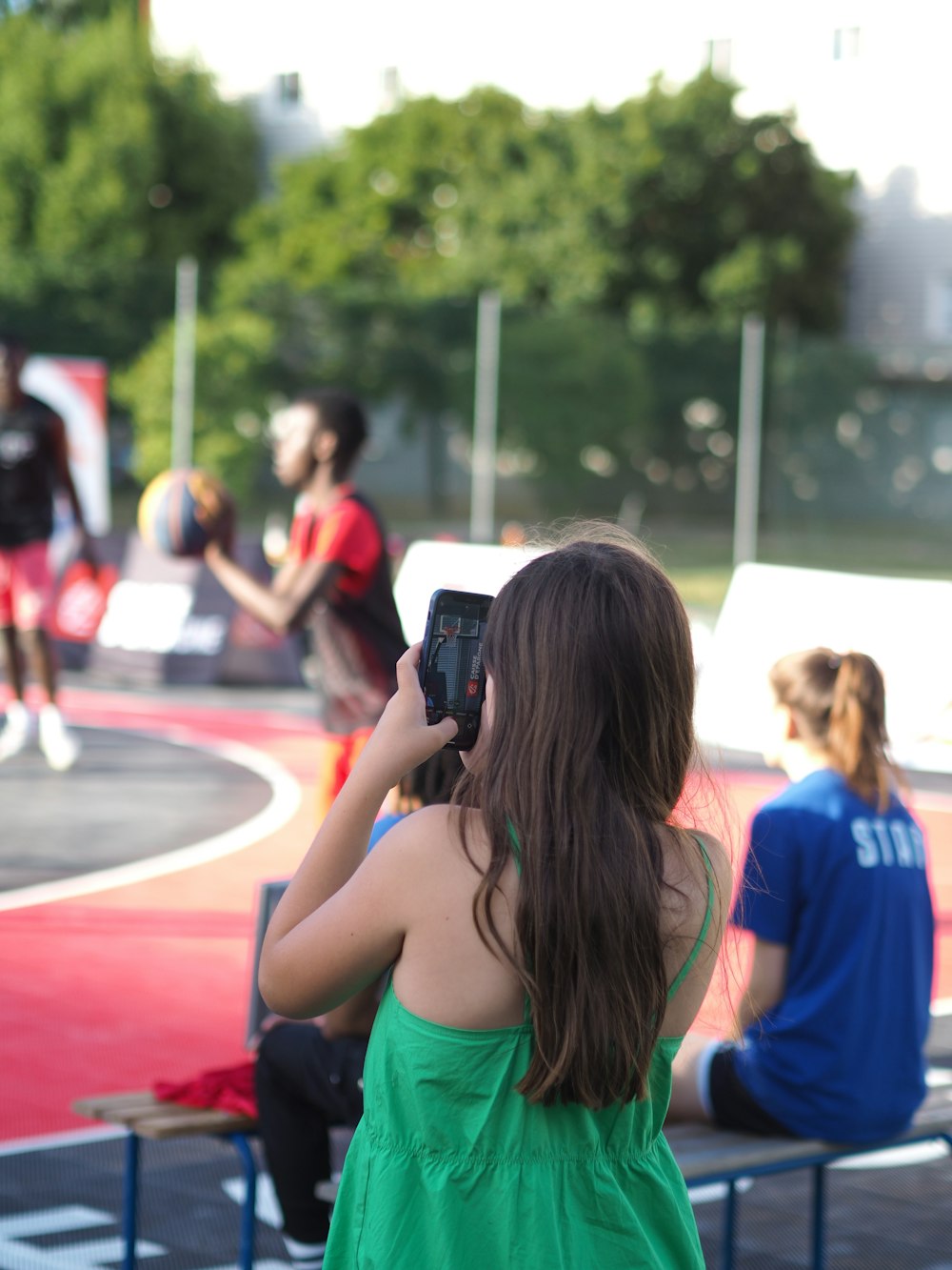 a woman taking a picture of a girl in a green dress