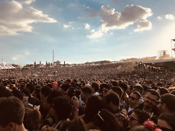 A crowd enjoying a music festival under a clear blue sky.