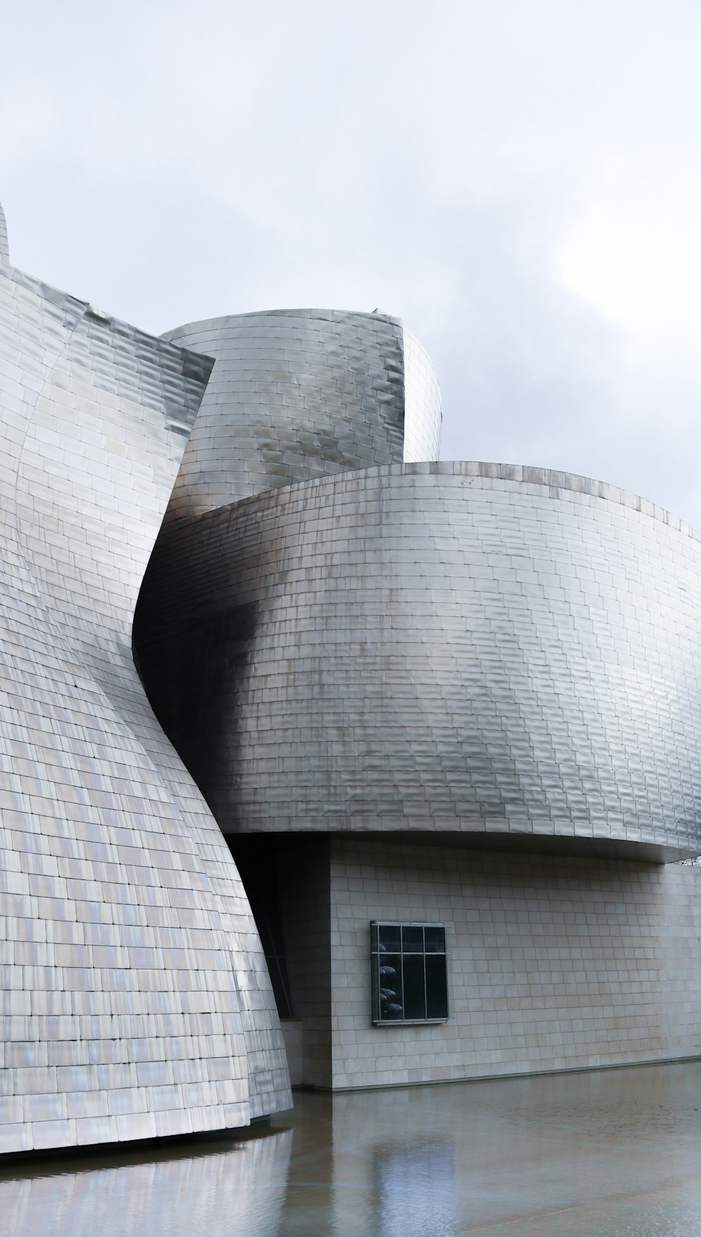 un gran edificio gris con el Museo Guggenheim Bilbao al fondo