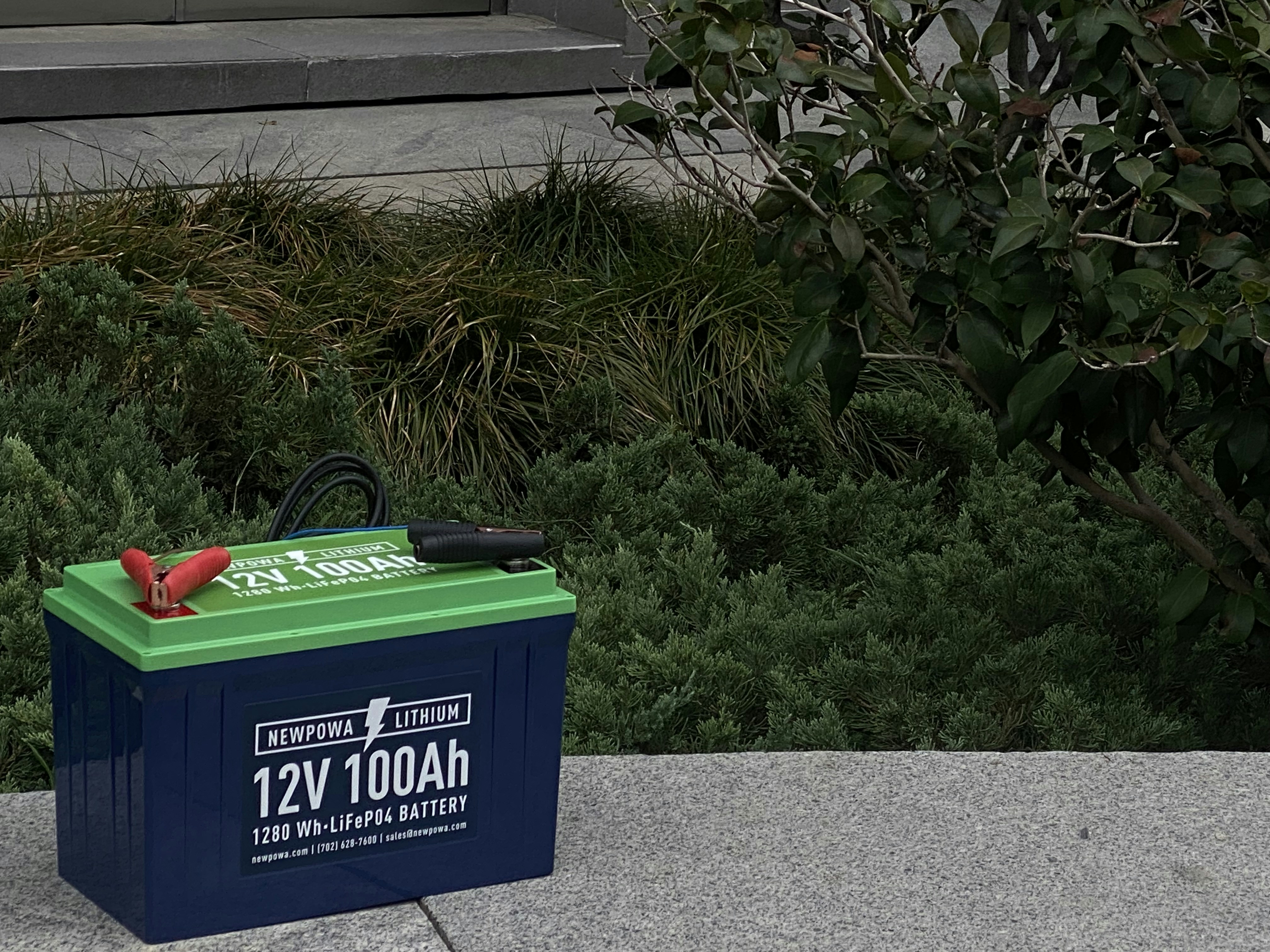 a green garbage can with a red handle and a green planter