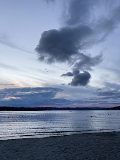 A serene lake reflecting the muted colors of a cloudy sky at twilight.