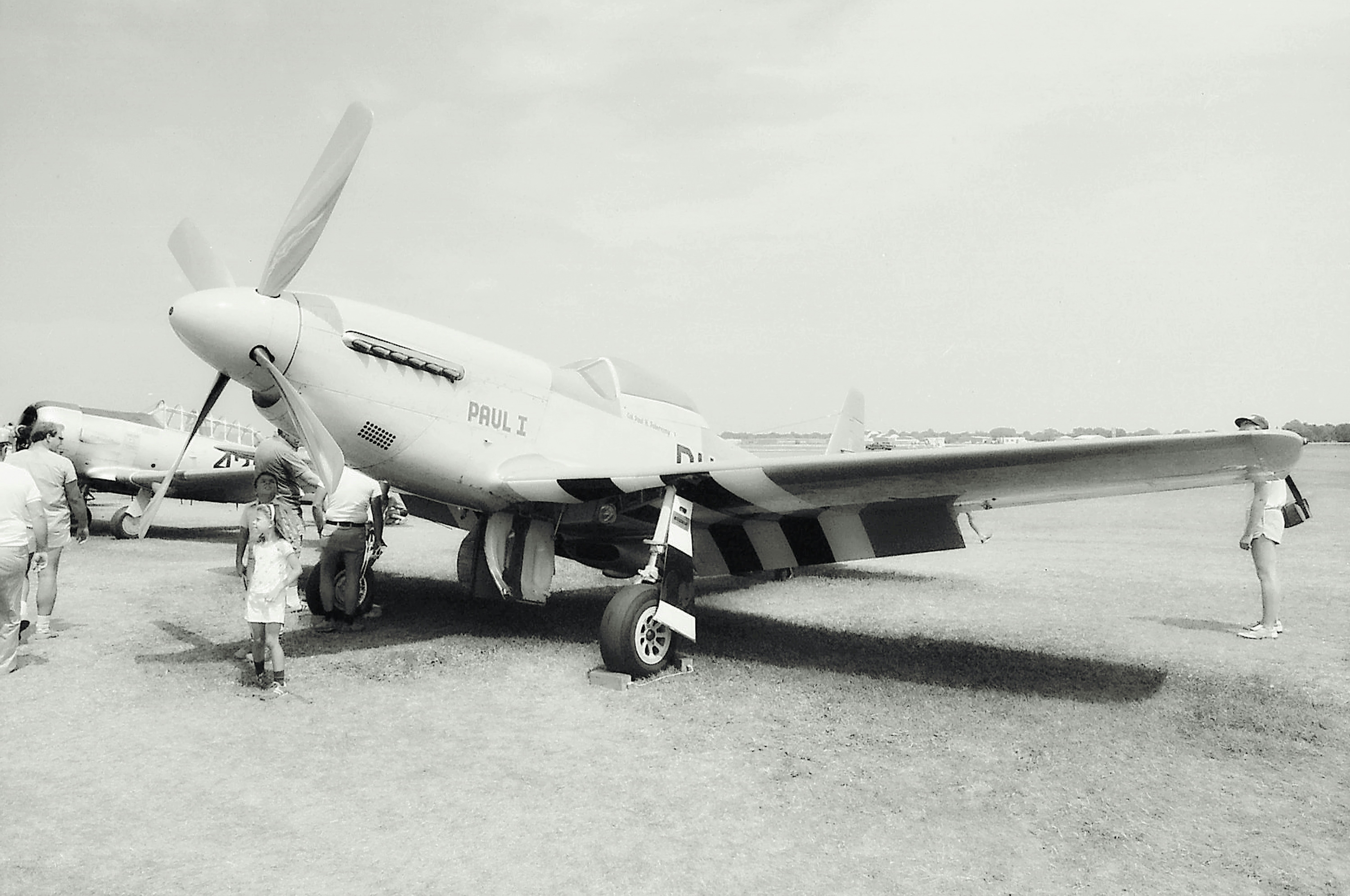 a group of people standing next to an airplane, P-51 Mustang at the Oshkosh Air Show. Photo was made from scanned 35mm film.