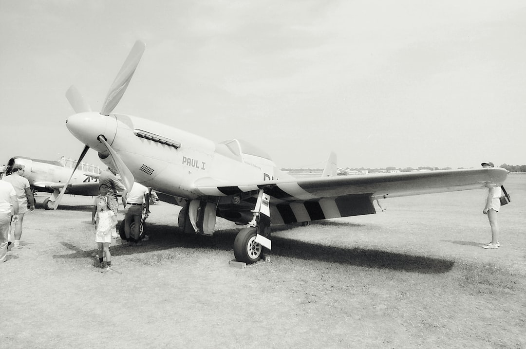a group of people standing next to an airplane, P-51 Mustang at the Oshkosh Air Show. Photo was made from scanned 35mm f