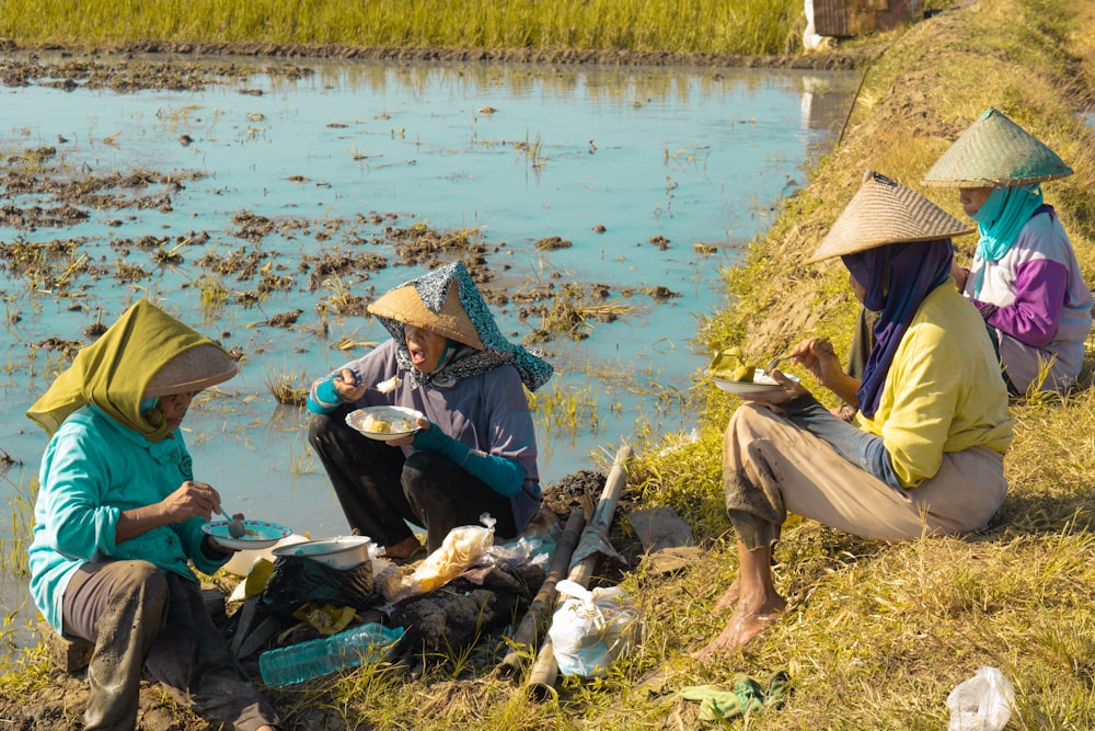 a group of people sitting next to a river