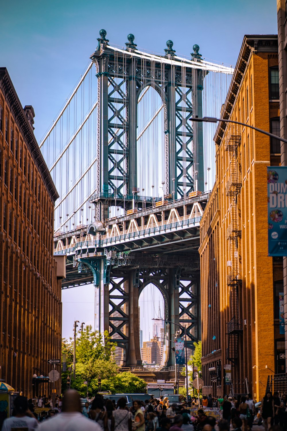 a large group of people walking on a street next to Manhattan Bridge