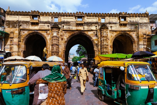 A lively street scene in Mumbai with colorful market stalls and the Gateway of India in the background.