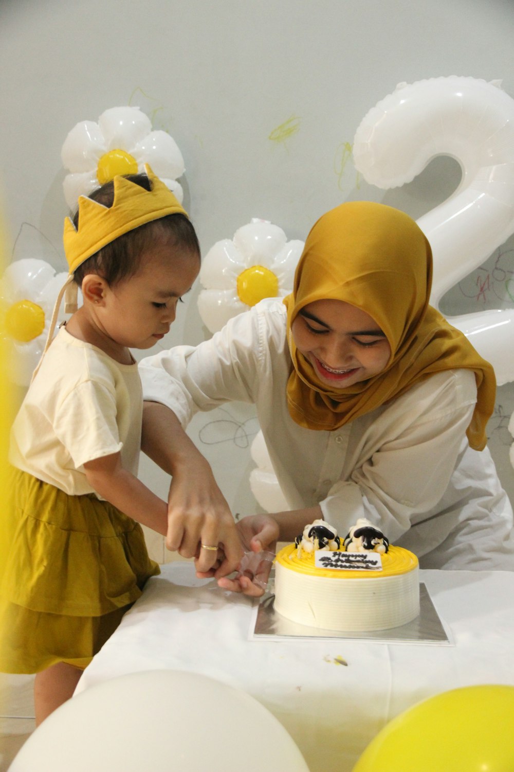 a person and a child cutting a cake