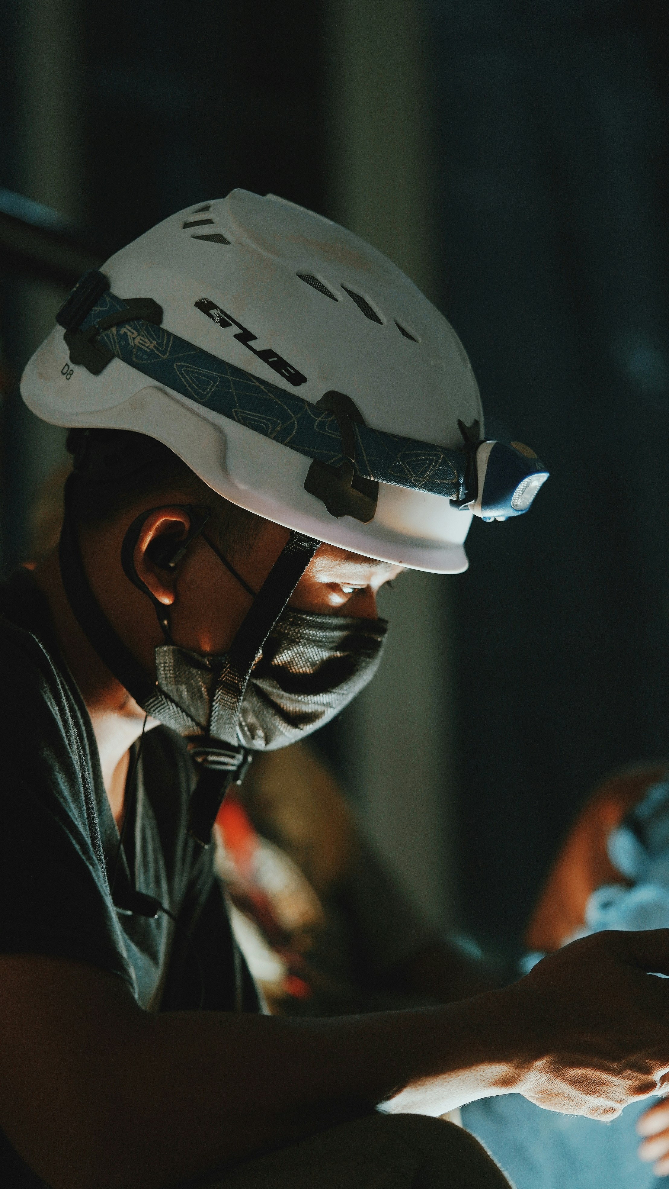 Full brim hard hat on dark workshop surface, strong directional lighting
