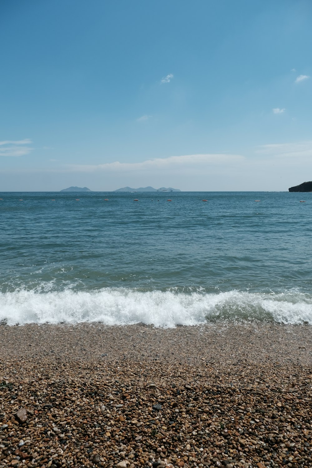 a rocky beach with a body of water in the background