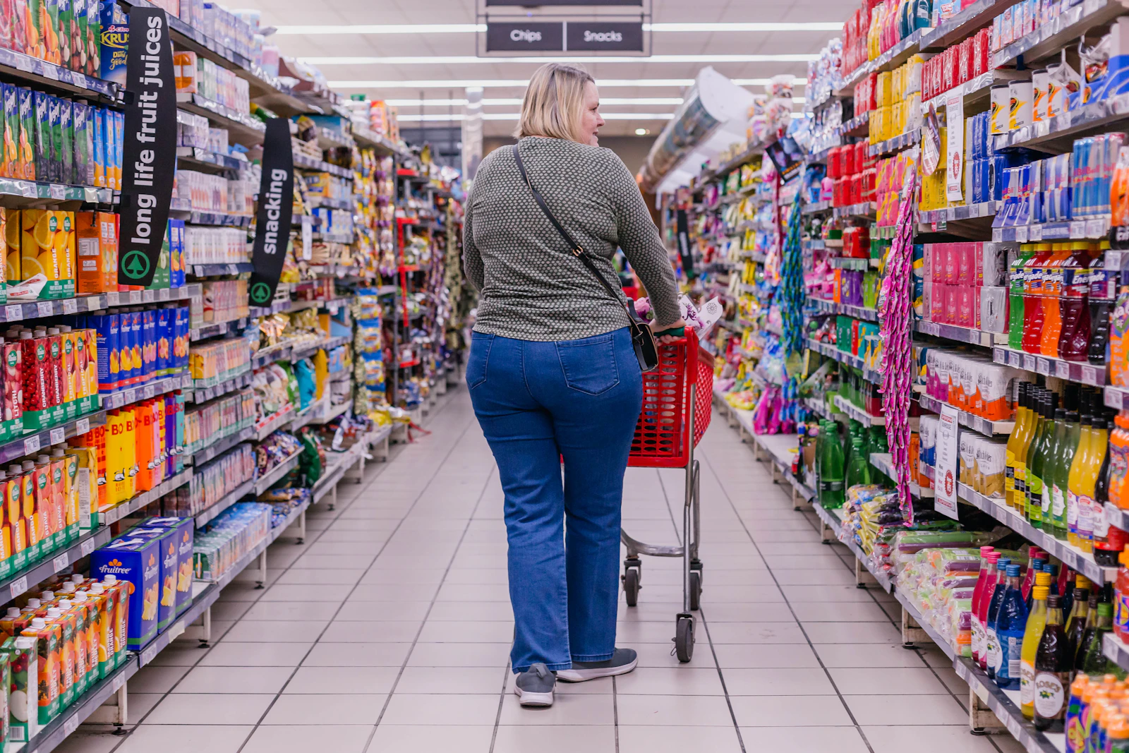Shopper pushing a cart down a retail store aisle