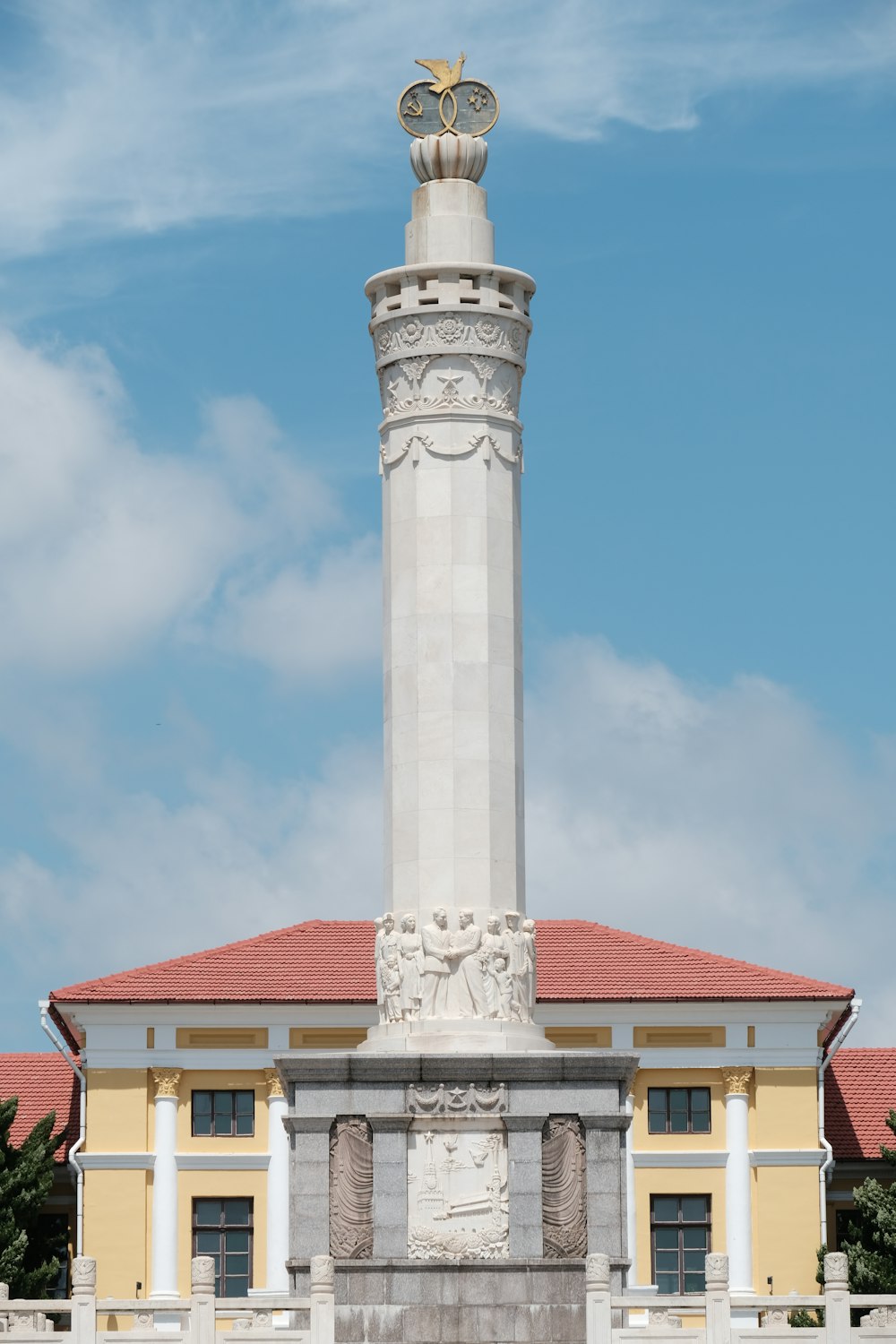 a tall white tower with a gold statue on top with Norah Head Light in the background