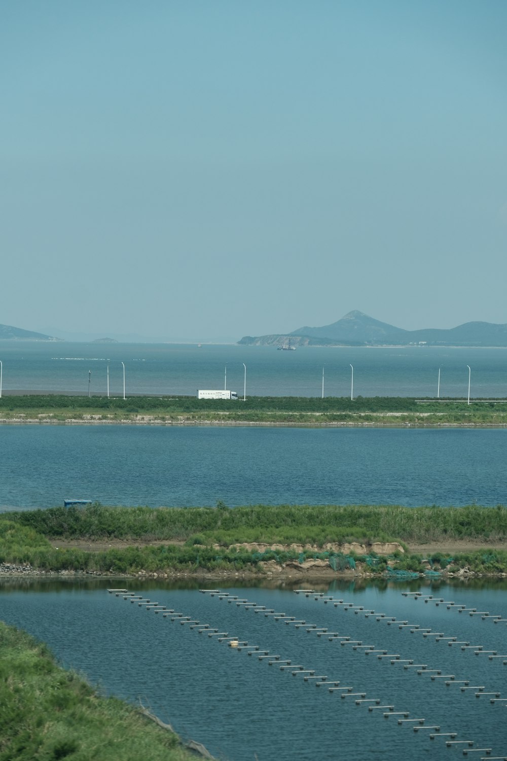 a body of water with grass and a land with a structure in the distance