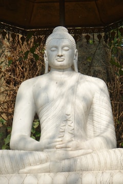 Marble statue of a serene deity standing gracefully in a garden.