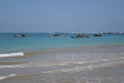 A small fishing boat gently rocking on calm turquoise waters at sunrise.