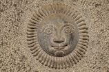 Detail of a carved stone piece reflecting the theme of sun and agriculture.