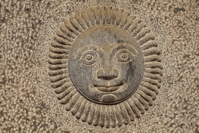 Detail of a carved stone piece reflecting the theme of sun and agriculture.