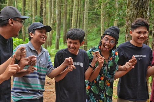 A group of colleagues laughing together during an outdoor team building challenge in a lush forest.