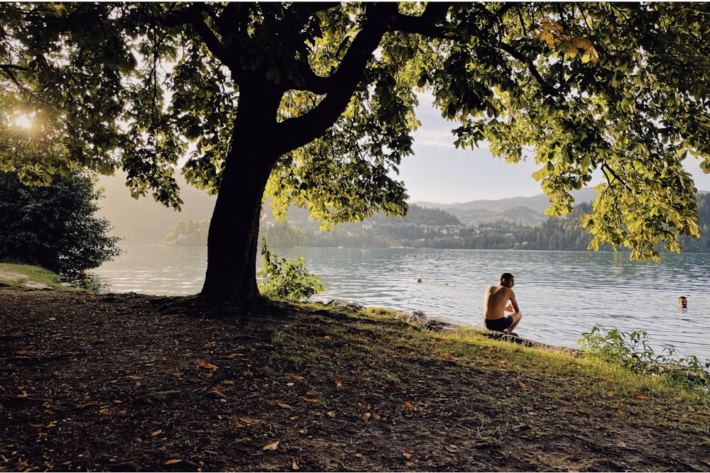 Eine Person, die auf einem Hügel an einem See sitzt