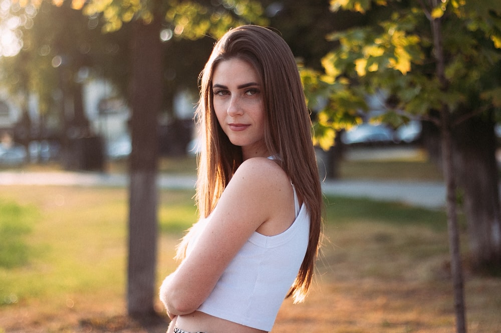 a woman with long hair standing in a park