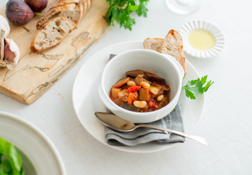 a bowl of soup with bread and a spoon on a table