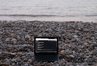 Ordenador de nómada digital sobre una playa de piedras