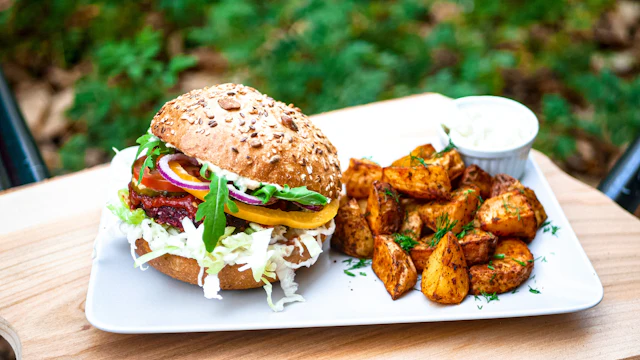 A plant-based burger with potato wedges and a dip