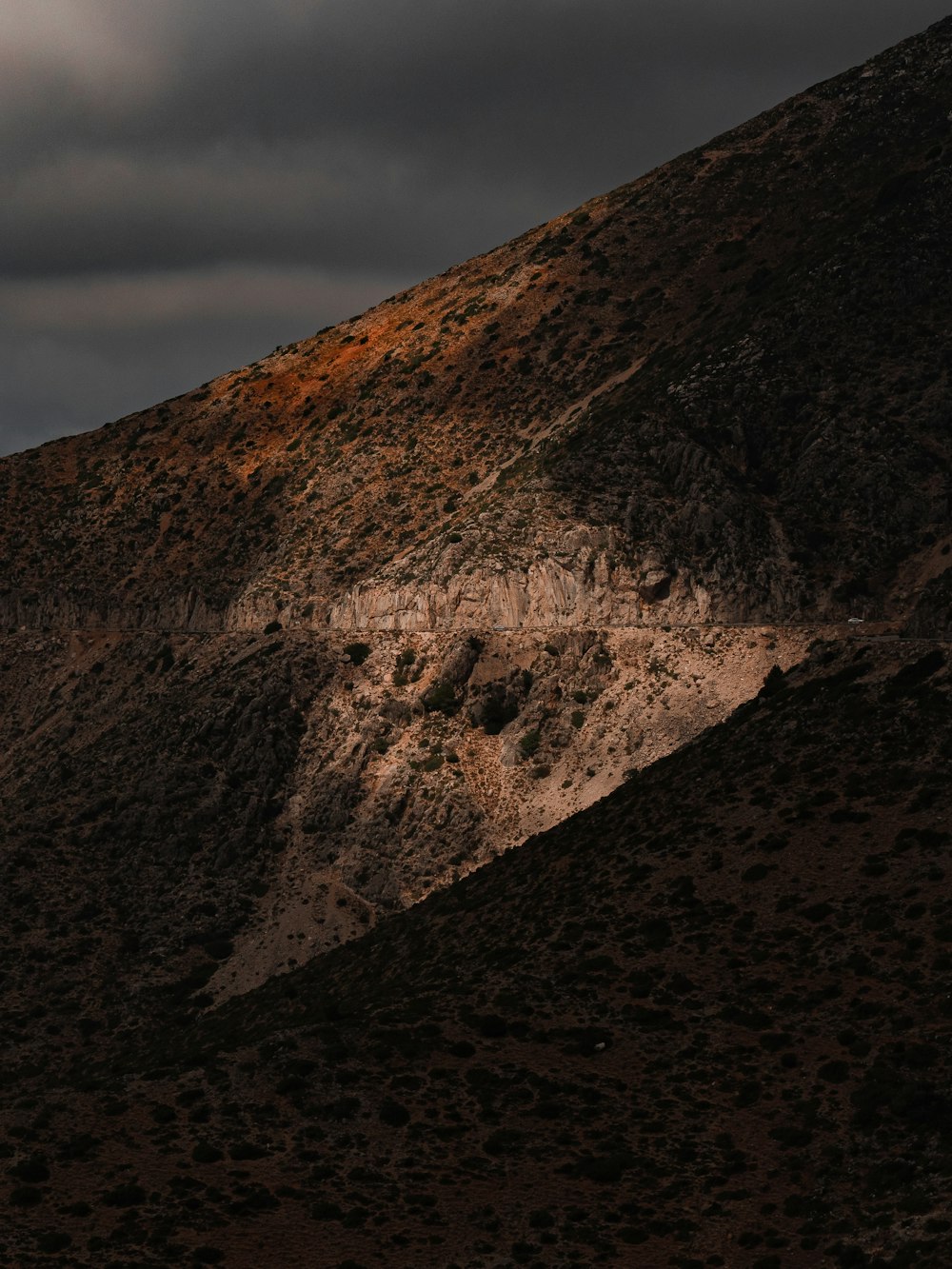 a rocky mountain with a cloudy sky