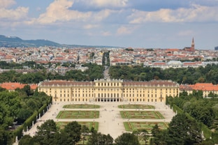 a large building with a courtyard and trees in front of it with Schönbrunn Palace in the background
