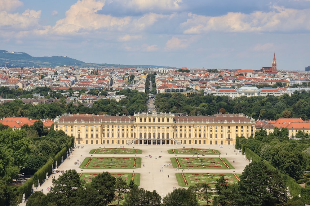 ein großes Gebäude mit Innenhof und Bäumen davor mit Schloss Schönbrunn im Hintergrund