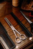 Close-up of scissors and comb on a wooden table in a home salon.
