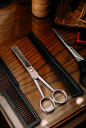 Sleek grooming kit with scissors, comb, and trimmer on a wooden surface.