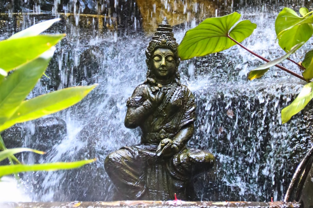 uma estátua de uma pessoa segurando uma folha em uma fonte