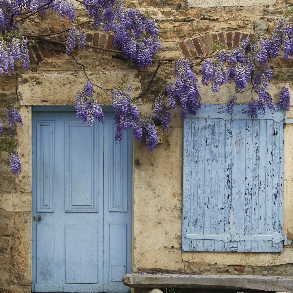 une porte bleue avec des fleurs violettes dessus