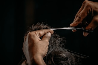 a person cutting a woman's hair with scissors