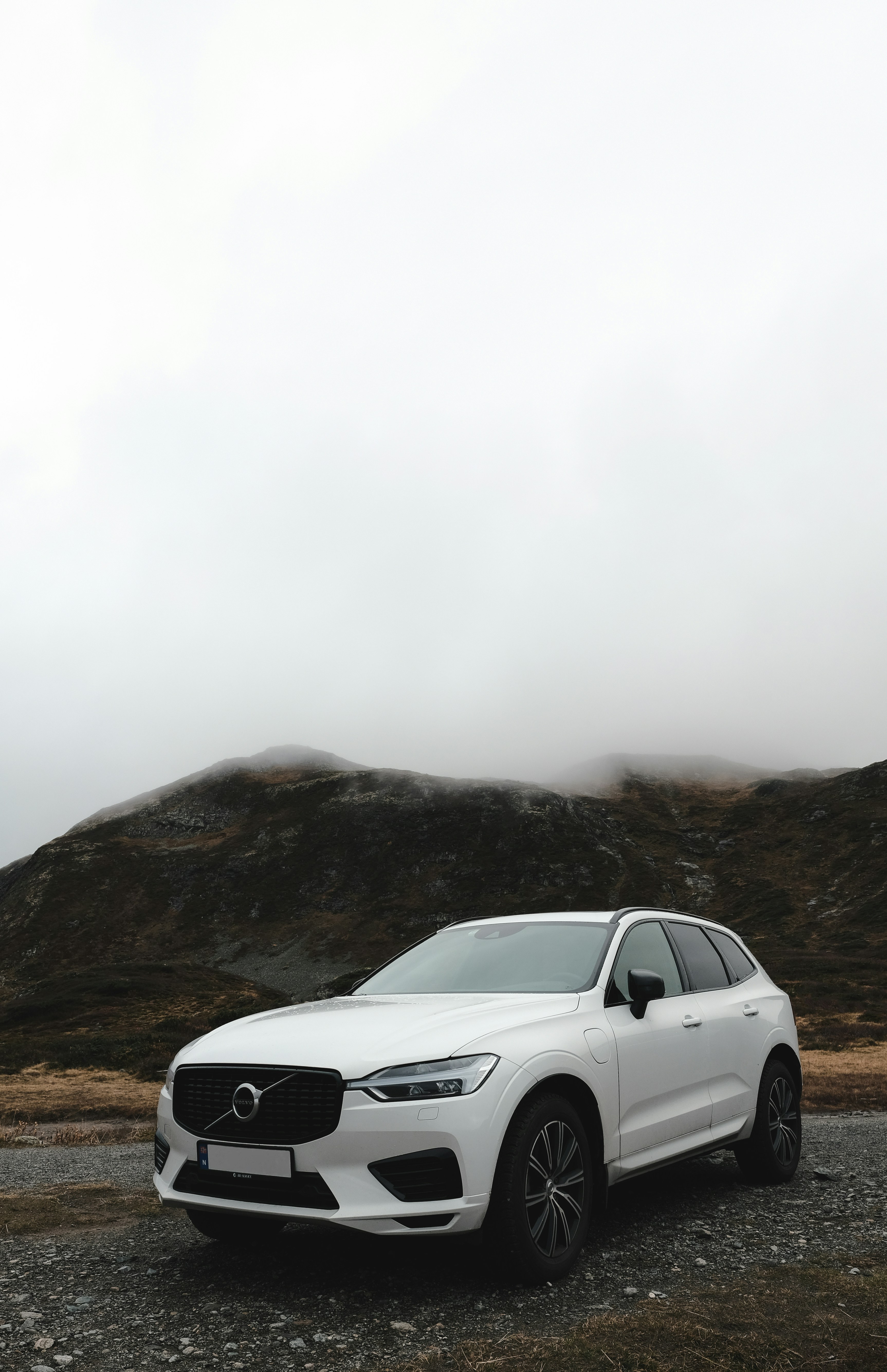 a white car parked on a dirt road with hills in the background