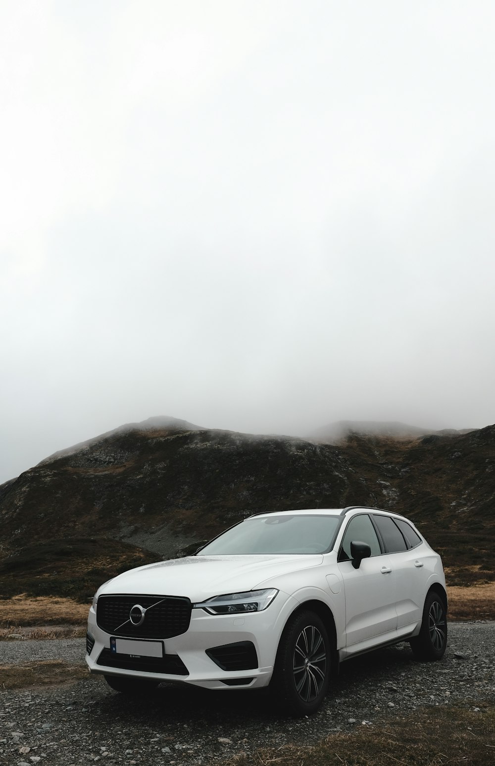 Un'auto bianca parcheggiata su una strada sterrata con le colline sullo sfondo