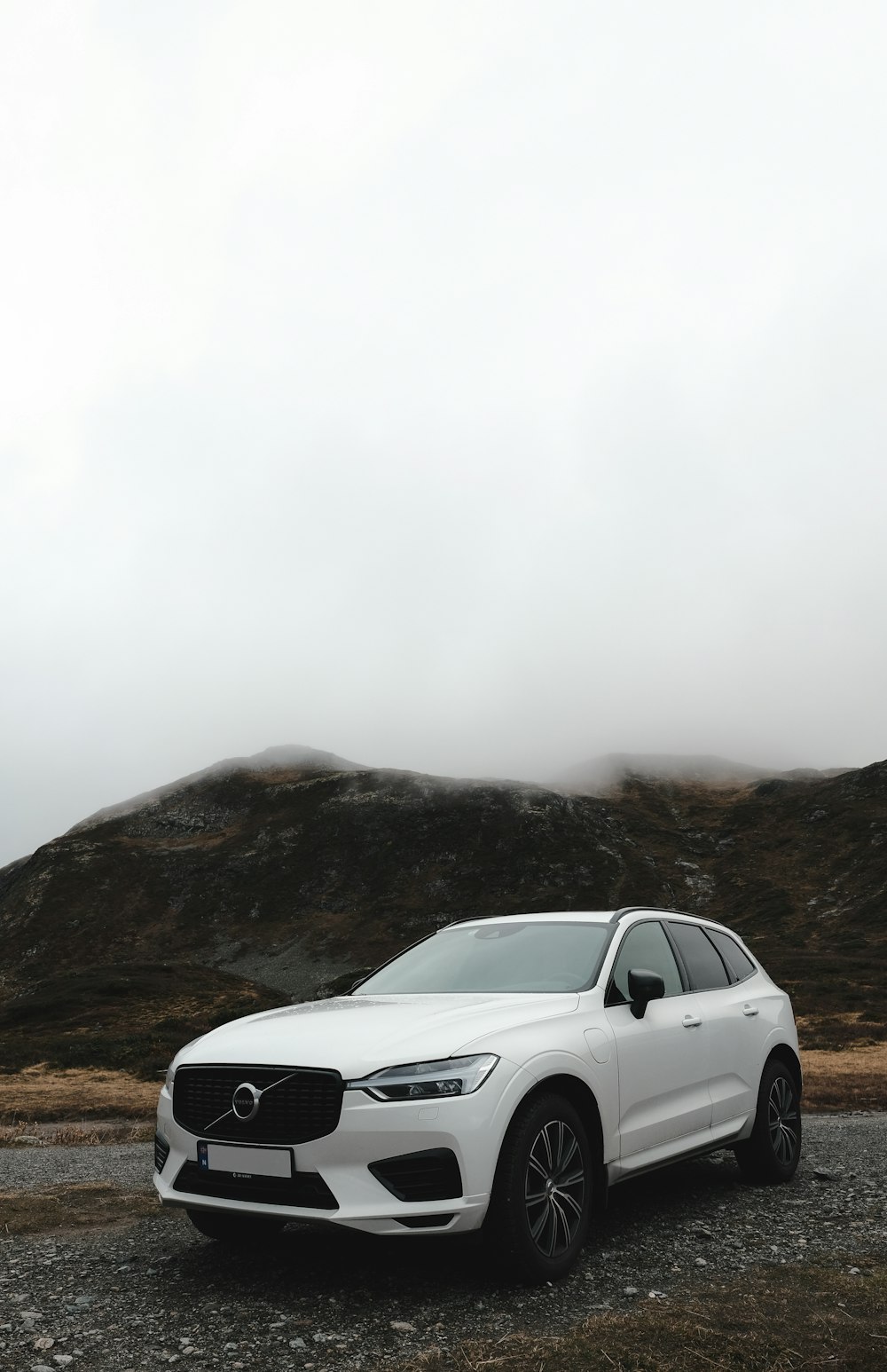 a white car parked on a dirt road with hills in the background