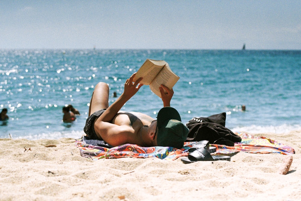 a person lying on a beach reading a book