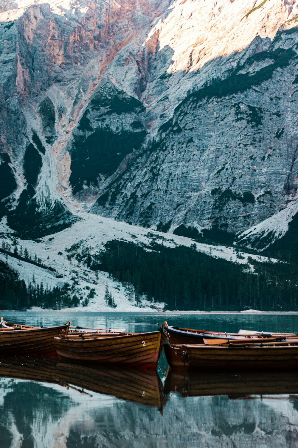 um grupo de barcos em um corpo de água por uma montanha rochosa