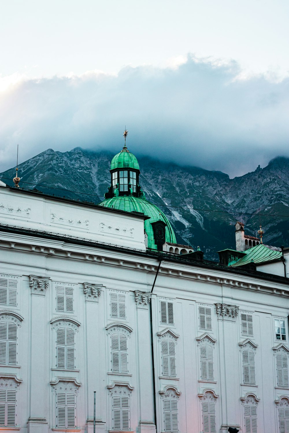 a building with a green roof and a mountain in the background