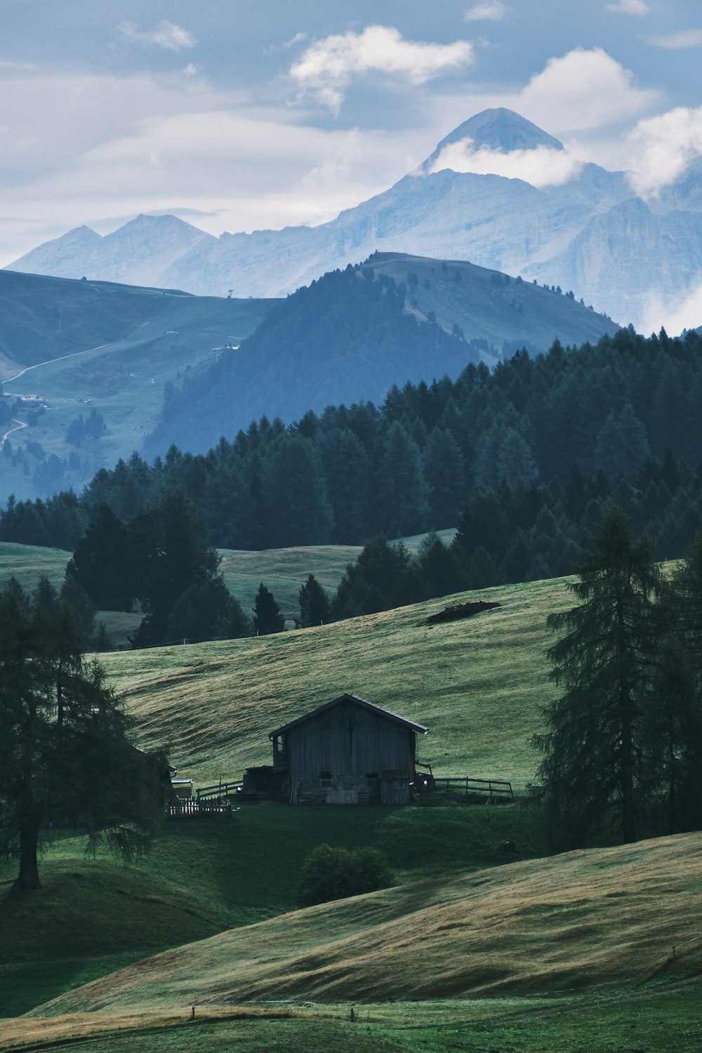 a small house in a valley with mountains in the background