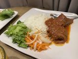 A warm, inviting lunch plate featuring rice, beans, salad, and a golden fried cutlet.
