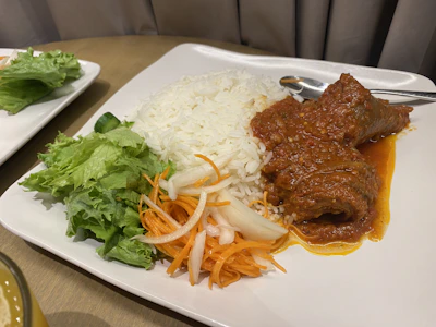 A generous portion of köfte served with rice and salad on a rustic plate.