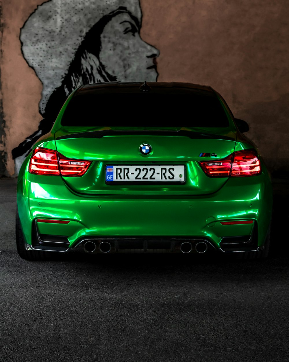 a green car parked in front of a rock wall