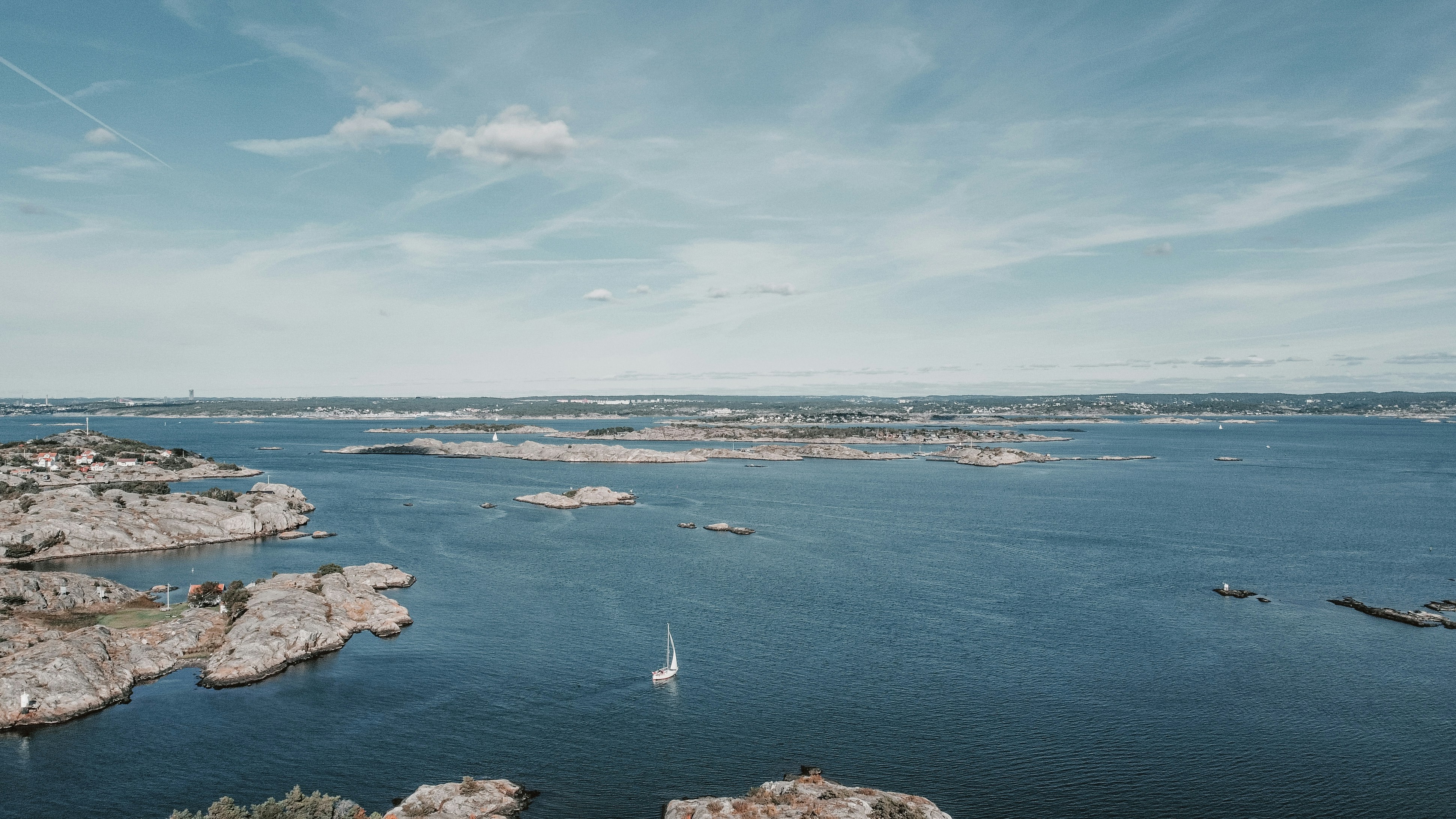 a body of water with rocks and a sailboat in it