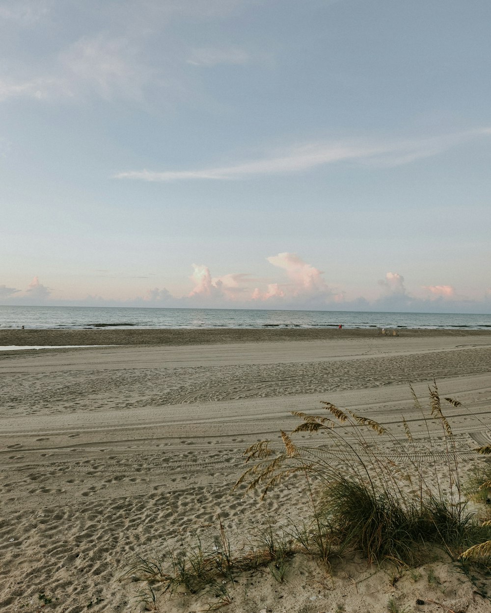 a sandy beach with water and clouds